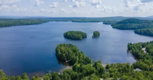 Vue aérienne du Lac Montjoie en Estrie montrant le lac, les îlots, les propriétés riveraines et le paysage naturel environnant