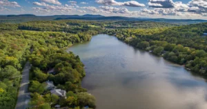 Vue aérienne du lac Miller en Estrie montrant les propriétés riveraines, les chalets au bord de l'eau et le paysage montagneux environnant.