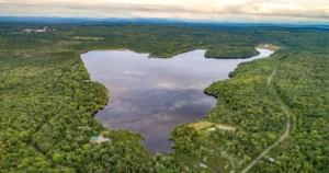Vue aérienne du lac Whitton en Estrie entouré de forêts, de propriétés riveraines et de paysages naturels.